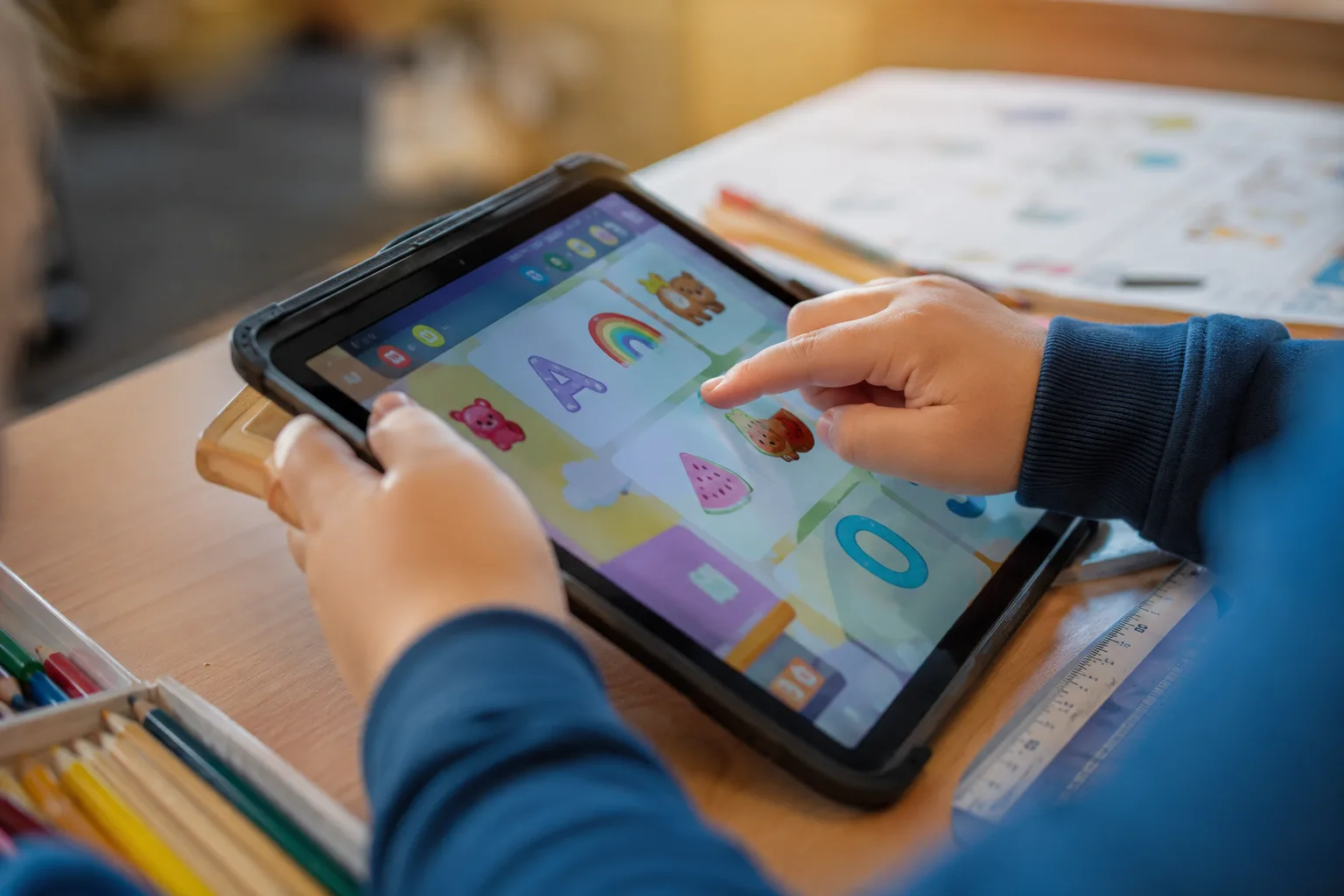 Nærbilde av barnehender som taster på en fargerik læringsapp på en iPad
